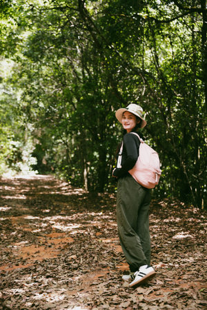 Young female traveler with backpack walking in national park or forest. recreation sport in nature. Female person bag, wave for hiking journey in woods. adventure in forest. trekking with backpackの写真素材