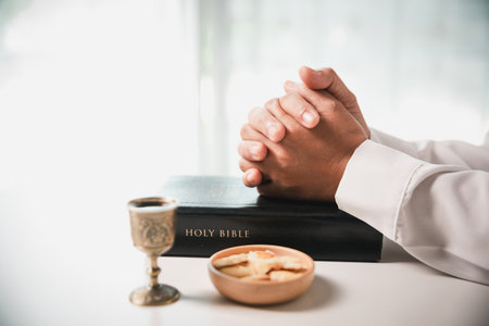 During the holy communion ceremony in church, a hand is extended in faith to receive the sacred sacrament, reflecting the spiritual and religious worship central to Christianity.の写真素材