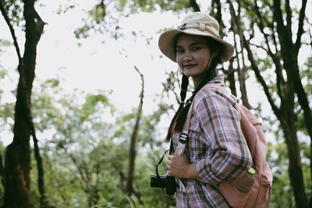 Young female traveler with backpack walking in national park or forest. recreation sport in nature. Female person bag, wave for hiking journey in woods. adventure in forest. trekking with backpackの写真素材