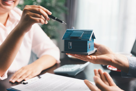 Woman real estate sale agent, client after signing agreement contract real estate with approved mortgage application form concerning mortgage loan offer, house insurance. contract agreement in officeの写真素材