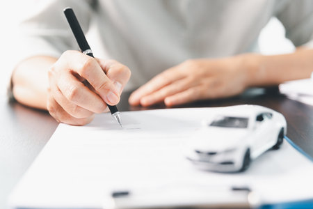 Sale agent deal to agreement successful car loan contract with customer and sign agreement contract Insurance car concept. Car dealer businesswoman signing car insurance document or lease paper.の写真素材