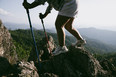 Hiking boot. Close up of female legs in boots on hiking trail on top of mountain outdoor. young woman reaching top of mountain. women feet wearing hiking boots on rock. Travel, vacation concept.の写真素材