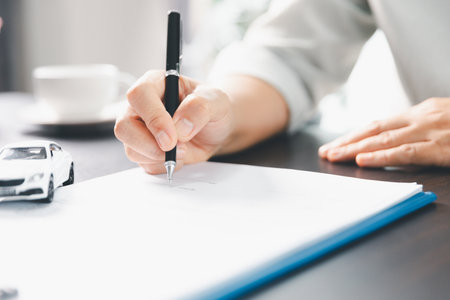 Sale agent deal to agreement successful car loan contract with customer and sign agreement contract Insurance car concept. Car dealer businesswoman signing car insurance document or lease paper.の写真素材
