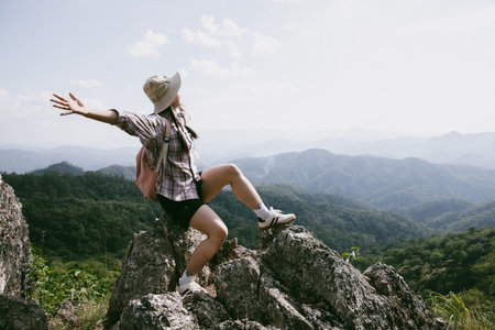 Woman hiker on top of mountain. Hiker with arms up on top of mountain successful young woman enjoying triumph. traveler exploring world. Hikers with backpacks relaxing. Sport and success concept.の写真素材