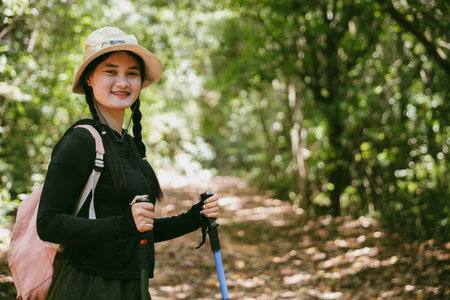 Young female traveler with backpack walking in national park or forest. recreation sport in nature. Female person bag, wave for hiking journey in woods. adventure in forest. trekking with backpackの写真素材