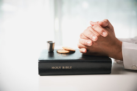 During the holy communion ceremony in church, a hand is extended in faith to receive the sacred sacrament, reflecting the spiritual and religious worship central to Christianity.の写真素材