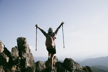 Woman hiker on top of mountain. Hiker with arms up on top of mountain successful young woman enjoying triumph. traveler exploring world. Hikers with backpacks relaxing. Sport and success concept.の写真素材