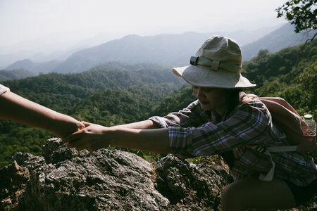 Two friends helping with teamwork trying to reach top of mountains during wonderful summer sunset. Teamwork couple hiking help each other trust assistance. Team of climbers two friends hiker.の写真素材