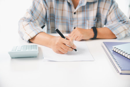 Accountant working on desk using calculator for calculate finance report in office. business finance, calculate tax by organizing financial documents, tracking income investment, accounting by hand.の写真素材