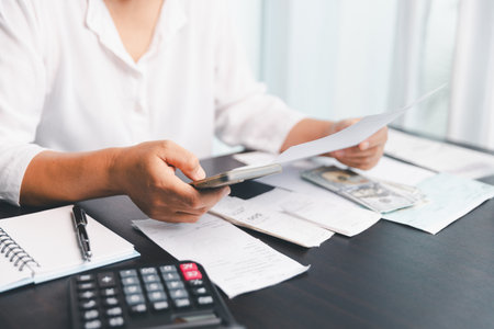 Using calculating machine, household carefully manages each bill and expense to plan financial...