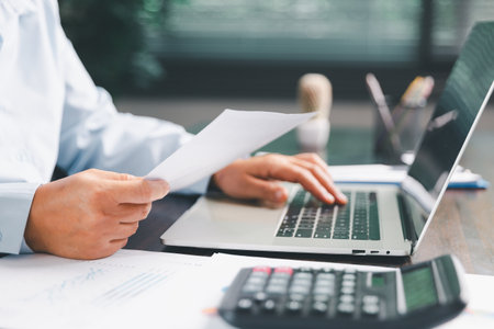 Office businesswoman hand to operate calculator analyzing financial data, counting costs on desk....