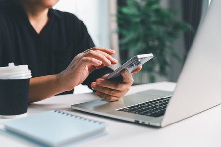 Close-up scene, a female seated at a table holds a smartphone, spending time on modern e-date...