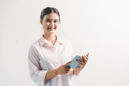Asian woman rejoicing, looking happy, fist pump gesture, standing over white background. young woman had happy, positive expression on her face, highlighted by bright smile.の写真素材