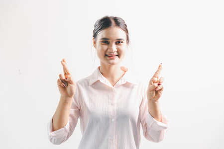 Asian woman rejoicing, looking happy, fist pump gesture, standing over white background. young woman had happy, positive expression on her face, highlighted by bright smile.の写真素材