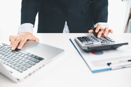 Accountant working on desk using calculator for calculate finance report in office. business...