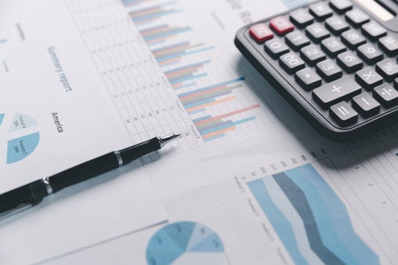 Auditor reviews financial statement and balance sheet on desk using a calculator, representing the concept of accounting, audit, and finance in preparing a detailed financial report for the business.の写真素材