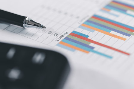 Auditor reviews financial statement and balance sheet on desk using a calculator, representing the...