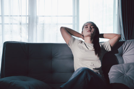 Sorrowful woman sat alone, overwhelmed by emotion, her sad and unhappy expression revealing deep...