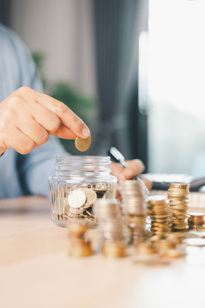 Hand places coin into saving jar, representing how smart finance, investment, banking practices turn...