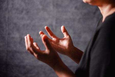 Christian woman lifts her hand in worship to pray, hope, faith, and deep belief in God defines core concept of religion. Praying hands with faith in religion, belief in God. Power of hope or love.の写真素材