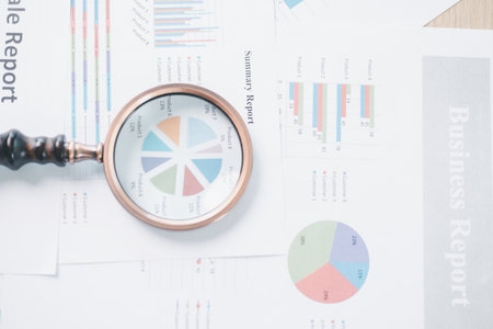 Magnifying glass with calculator and pen on financial reports with charts, graphs at office desk....