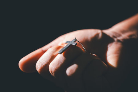 Dark silence of the church, a Christian lifts their hand in prayer to God, a symbol of worship, faith, and hope-embracing the spiritual concept of religion and believing in Jesus Christ.の写真素材