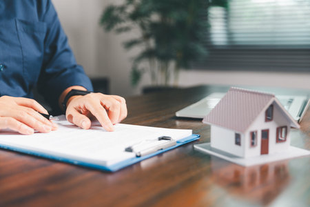 Female hand holds small miniature toy house, symbolizing woman dream of moving into her own home-real estate concept represents property investment, mortgage planning, insurance for secure future.の写真素材