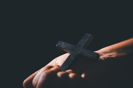 Dark silence of the church, a Christian lifts their hand in prayer to God, a symbol of worship, faith, and hope-embracing the spiritual concept of religion and believing in Jesus Christ.の写真素材
