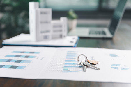 House model placed on table alongside coins, paperwork symbolizes real estate investment, property...