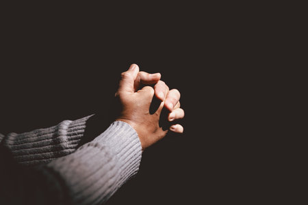Person clasping hands in prayer, symbolizing faith, hope, spirituality, devotion, inner strength,...