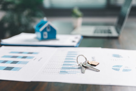 House model placed on table alongside coins, paperwork symbolizes real estate investment, property...