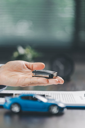 Business office, woman employee finalizes deal with client, handing over car key after signing...