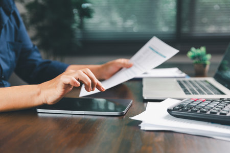 Office businesswoman hand to operate calculator analyzing financial data, counting costs on desk....