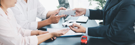 Panorama of businessman counting cash during car loan contract signing with vehicle models, key and...