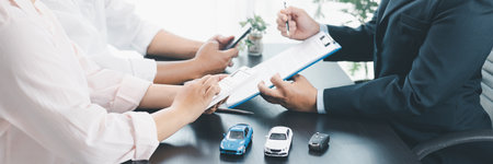 Panorama view of business meeting with car loan agreement, dealer showing calculator to customers at...