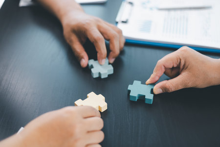 Business teamwork concept with people holding wooden puzzle pieces together, symbol of...