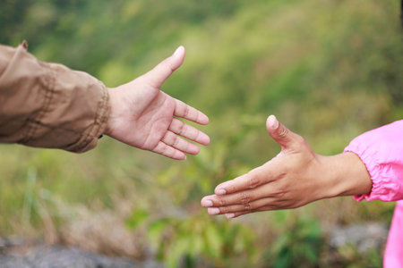Close-up of hiker reaching out hand for support, symbol of teamwork, leadership, trust, helping, motivation, encouragement, success and outdoor adventure lifestyle.の写真素材