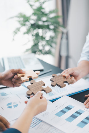 Business teamwork concept with people holding wooden puzzle pieces together, symbol of...