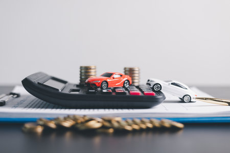 Red and white car models with open doors positioned beside stacked coins, symbolizing car loan, auto...