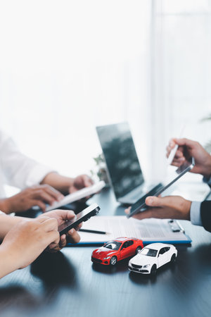 Car loan officer explaining contract details to customer with calculator, key and toy car on table, concept of auto finance, leasing, insurance, payment plan and business agreement.の写真素材