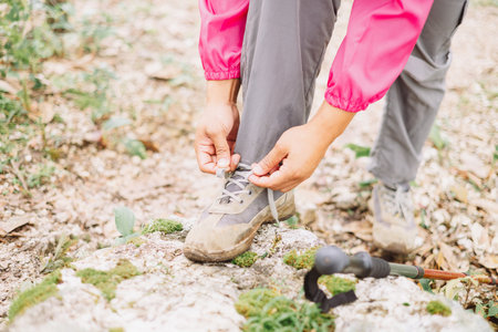 Close up of hiker tying shoelaces on sneaker with trekking pole in forest, symbol of preparation, adventure, outdoor lifestyle, hiking, journey and exploration in nature trail. adventure hikingの写真素材