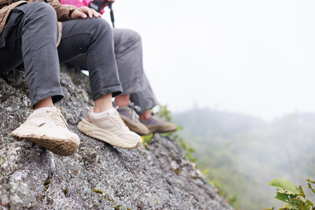 Close up of hiker resting on rocky cliff in hiking shoes, symbol of adventure, outdoor lifestyle, challenge, exploration, determination, nature journey and freedom in mountain travel.の写真素材