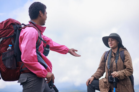 Two hikers on rocky mountain peak helping each other climb, symbol of teamwork, leadership, support,...