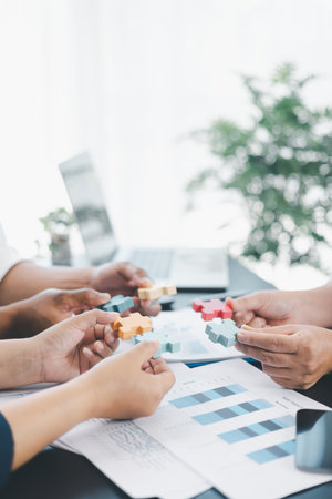 Business teamwork concept with people holding wooden puzzle pieces together, symbol of collaboration, strategy, problem solving, partnership and corporate success in modern office. business teamwork.の写真素材