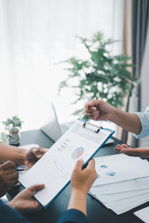 Business teamwork reviewing financial report with charts and graphs in modern office, colleagues discussing analysis, planning strategy, growth and corporate success with documents and technology.の写真素材