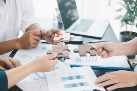 Business teamwork concept with people holding wooden puzzle pieces together, symbol of...