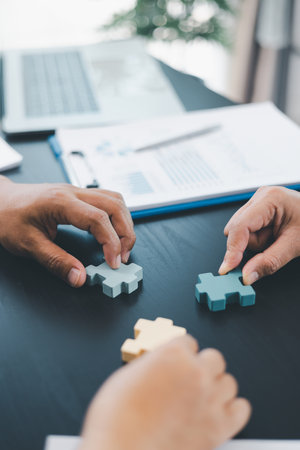 Business teamwork concept with people holding wooden puzzle pieces together, symbol of...