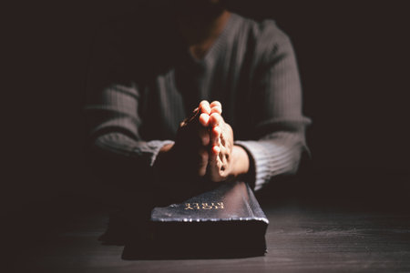 Hands clasped in prayer over the Holy Bible, symbolizing faith, devotion, Christianity, hope and spiritual strength through God Word, worship, meditation and encouragement.の写真素材