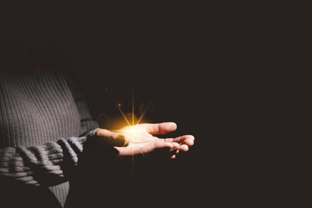Hands holding glowing light, symbolizing hope, healing, faith, inspiration, spiritual energy, new beginning, miracle, inner strength and positive transformation from darkness to light.の写真素材