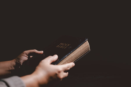 Hands clasped in prayer over the Holy Bible, symbolizing faith, devotion, Christianity, hope and spiritual strength through God Word, worship, meditation and encouragement.の写真素材